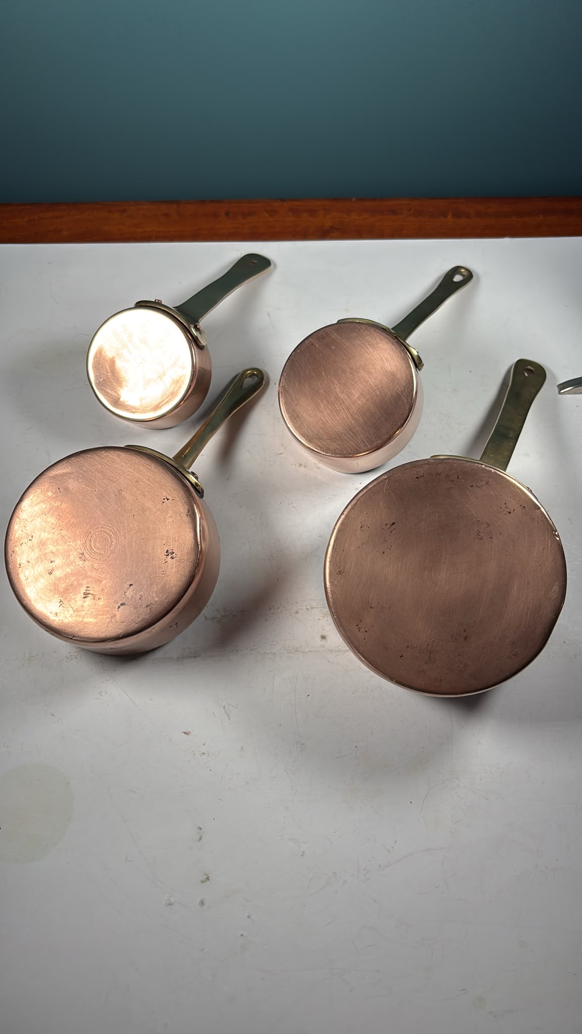 An image of A set of 4 graduated copper mini saucepans with brass handles