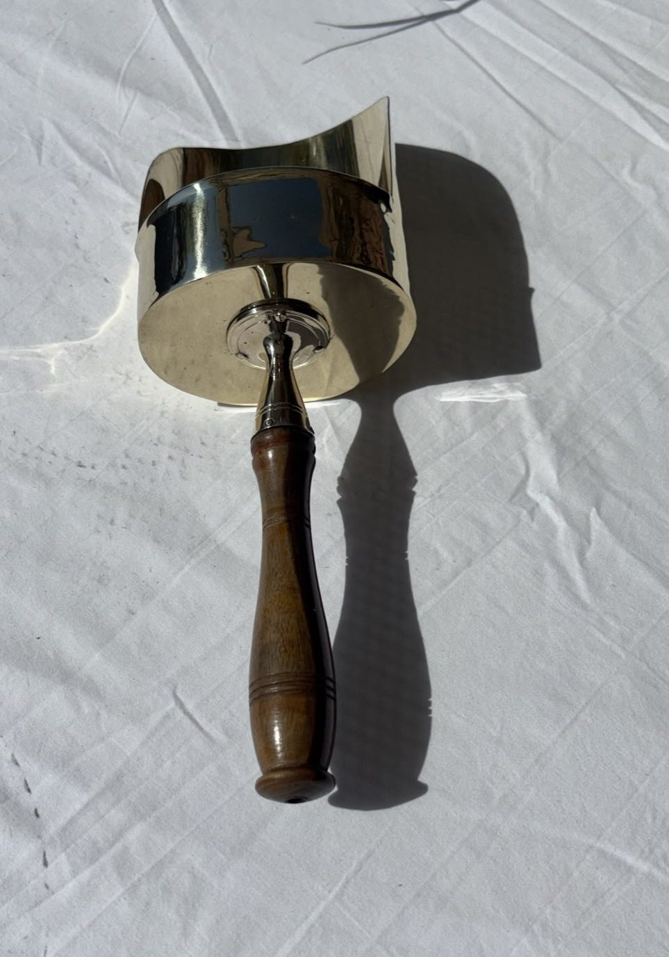 Image of A brass scoop with polished, wooden handle